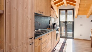 A modern kitchen with wooden cabinets, a black countertop, and a large window. - Holiday Home 'Sam Fiamet' with Mountain View, Shared Garden and Wi-Fi (GROSIO)