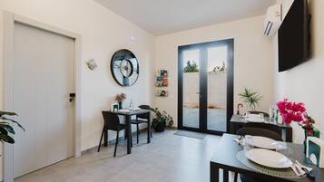 Un comedor moderno con una mesa dispuesta para dos personas, un reloj en la pared y un ventanal corredero que da al exterior.