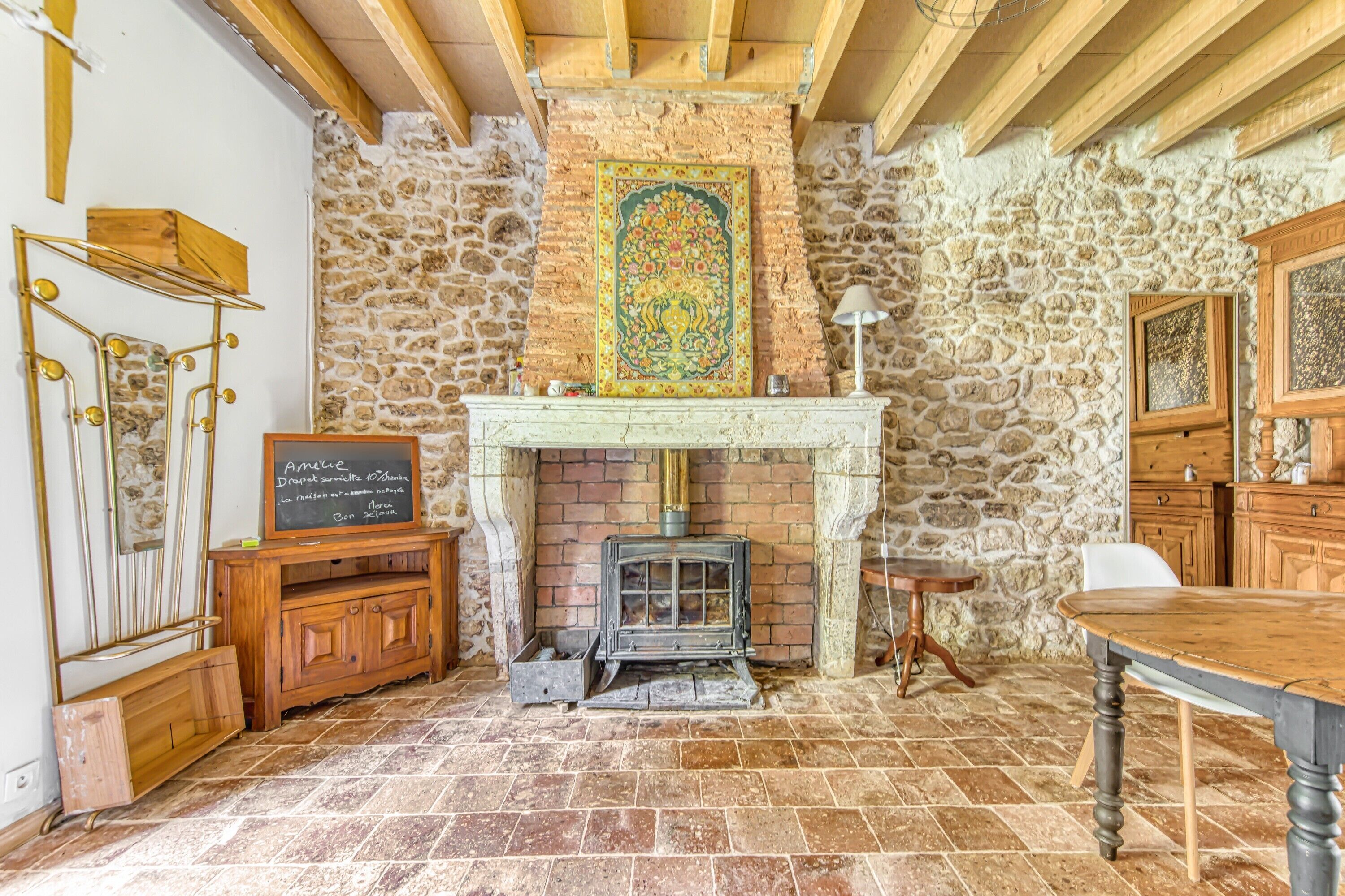 Ein rustikaler Raum mit Steinwand, Kamin, Holztisch und einer Bank.