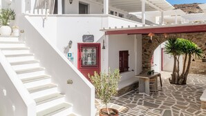 Un edificio blanco con puerta roja, una escalera y suelo de piedra.