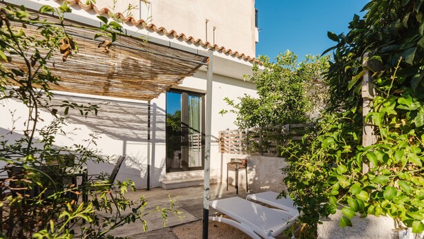 Um pátio com pérgola, área de estar ao ar livre e vista para um edifício.