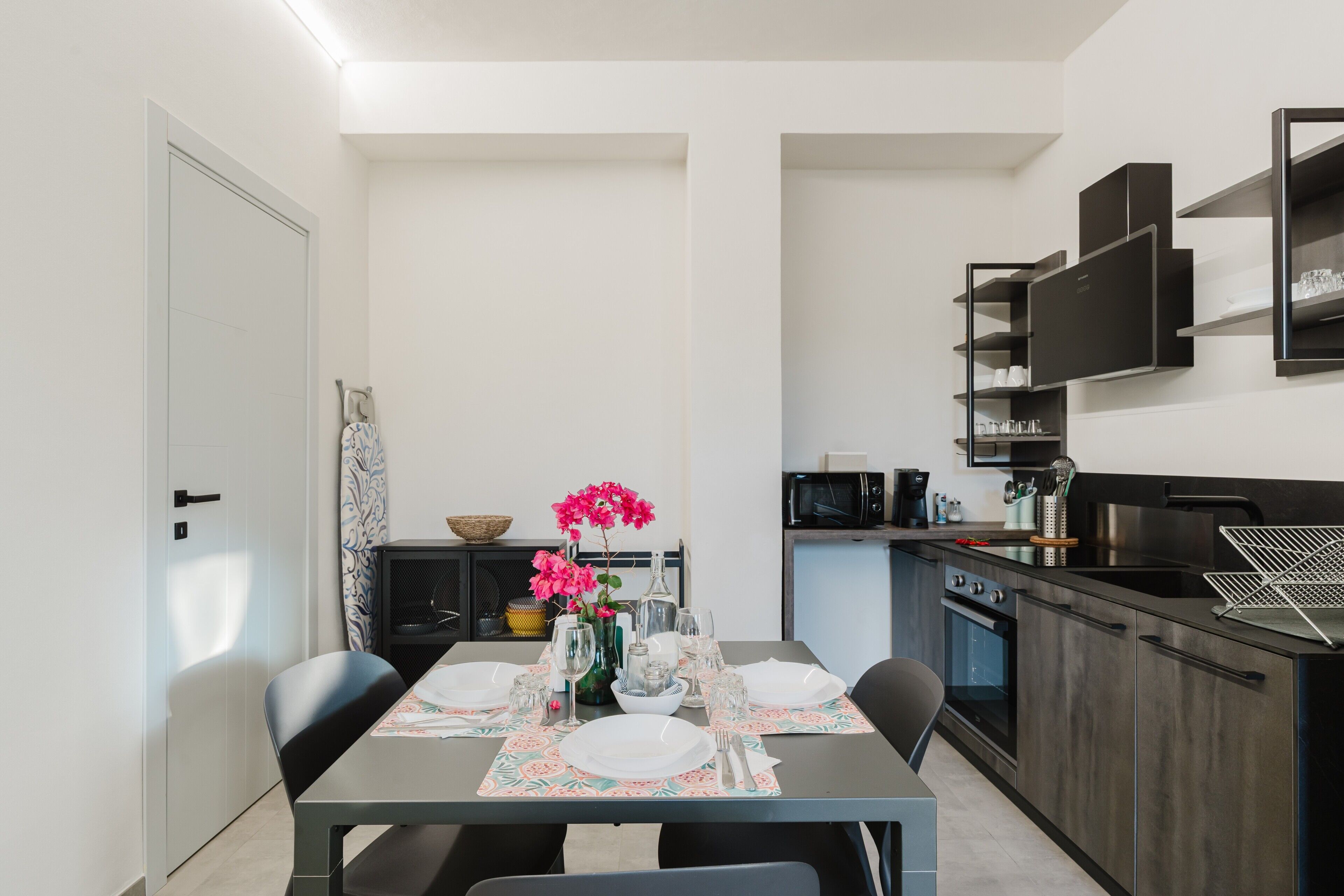 Una cocina compacta con electrodomésticos modernos, un comedor con una mesa dispuesta para dos personas y un pequeño rincón de estar.