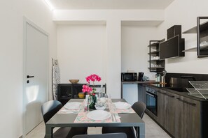 A compact kitchen with modern appliances, a dining area with a table set for two, and a small seating area.