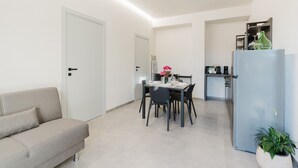Cozinha moderna com mesa de jantar, cadeiras e geladeira.