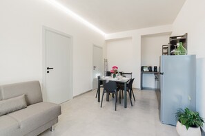 A modern kitchen with a dining table, chairs, and a refrigerator.