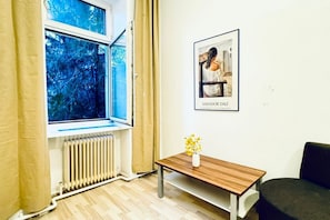 A room with a window, radiator, wooden table, and a framed picture on the wall.