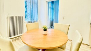 A round wooden table with four chairs, a potted plant, and a radiator.