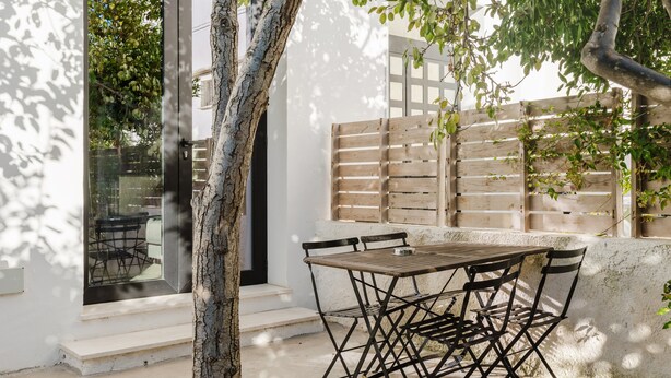 Eine Terrasse mit Tisch und Stühlen, ein Holzzaun und ein Baum.