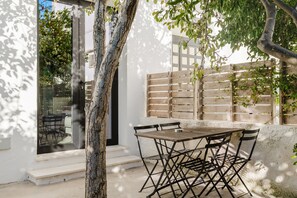 Un patio con una mesa y sillas, cerca de una valla de madera y un árbol.