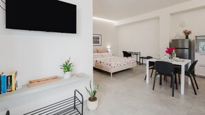 Eine moderne Wohnung mit Flachbildfernseher, einem Bett, einem Essbereich und einer Küchenzeile.