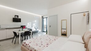 Ein modernes Hotelzimmer mit Bett, Nachttisch und Blick auf den Speiseraum.