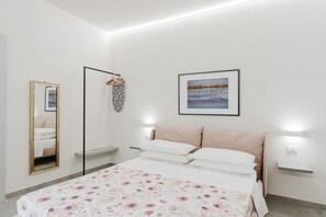 Une chambre à coucher avec un lit, un miroir, un tableau accroché au mur et des lampes de chevet.