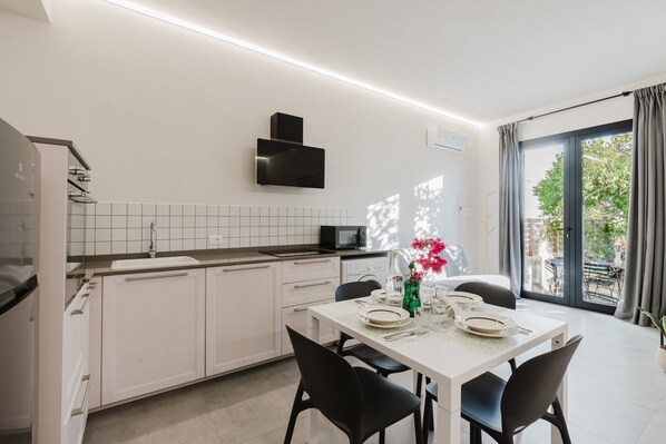 Una cocina moderna con alacenas blancas, un microondas y un comedor con una mesa dispuesta para dos.