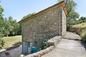 A stone building with a sloped roof, a small door, and a blue gate. - House in Provence in a Former Fulling Mill (Entrepierres)