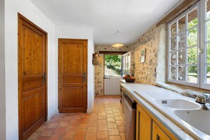 A kitchen with wooden doors, a large window, and a tiled floor.