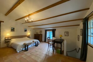 A bedroom with a bed, bedside tables, a desk, a chair, a window with curtains, and a chandelier. - House in Provence in a Former Fulling Mill (Entrepierres)