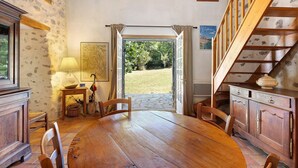 A dining area with a wooden table, chairs, a lamp, and a view of the outdoors. - House in Provence in a Former Fulling Mill (Entrepierres)