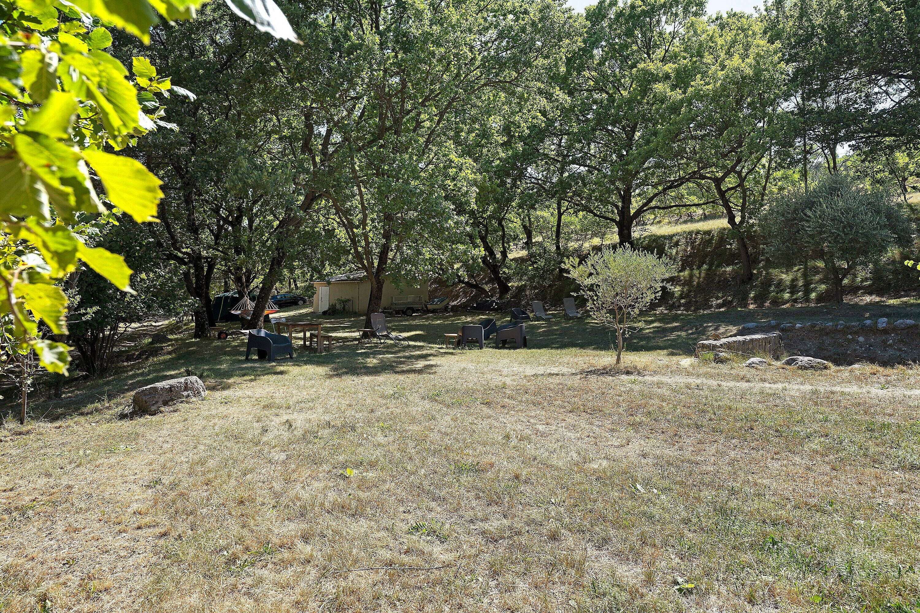 Un espacio al aire libre con césped, árboles y un pequeño edificio, probablemente una cabaña o refugio.