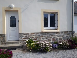 Un edificio con puerta blanca, una ventana y base de piedra.