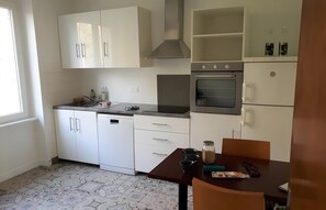 Una cocina moderna con armarios blancos, horno empotrado y una mesa con sillas.