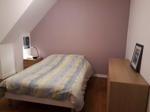 Ein Schlafzimmer mit einem Bett, einem Nachttisch, einem Schreibtisch und einem Wandregal.