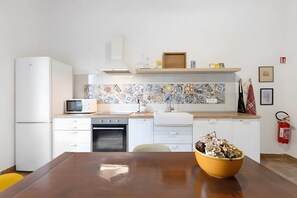 Une cuisine moderne avec des appareils électroménagers blancs, un four à micro-ondes et un évier. Un extincteur est fixé au mur.