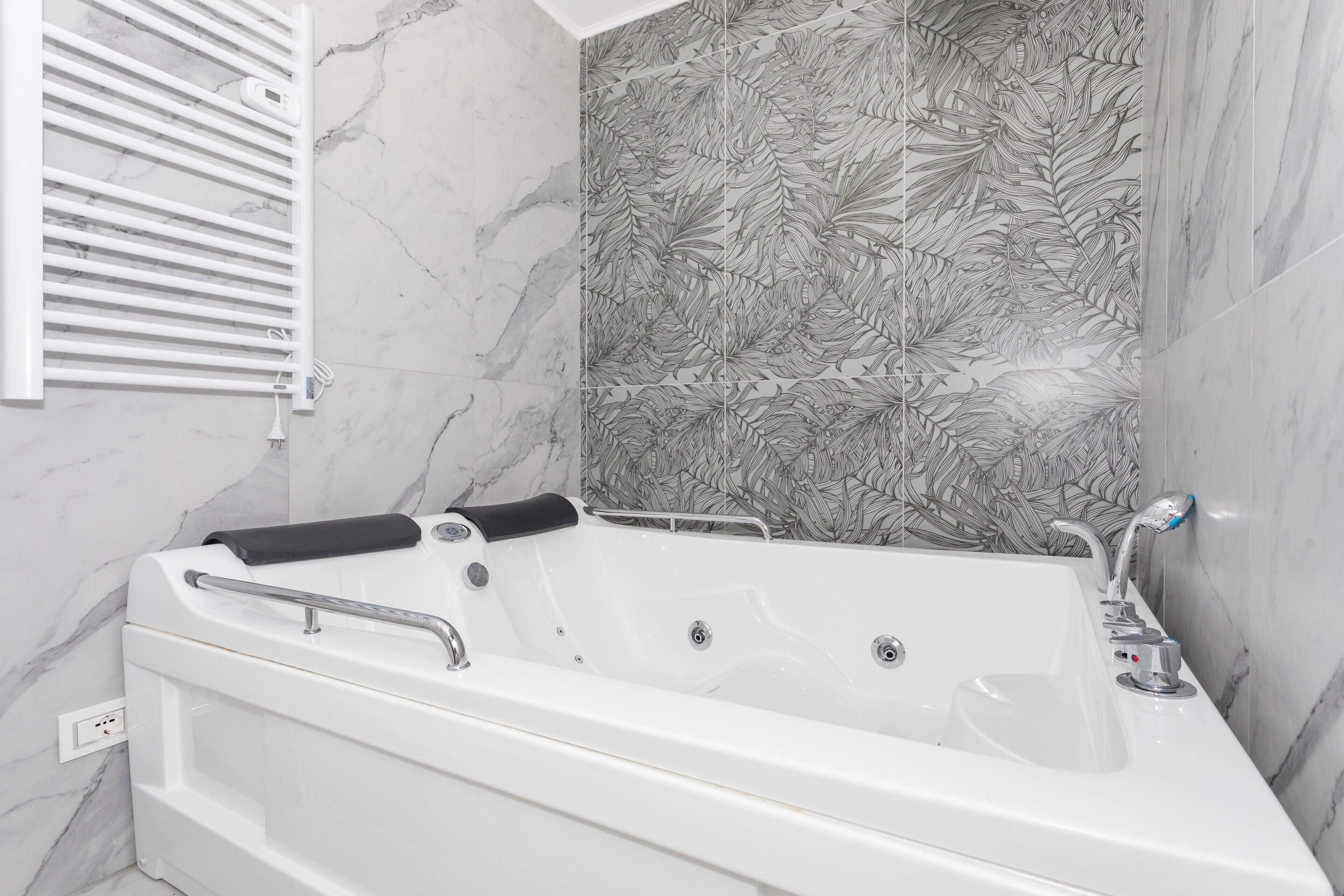 A modern bathroom with a freestanding bathtub, a handheld showerhead, and a wall-mounted heater.