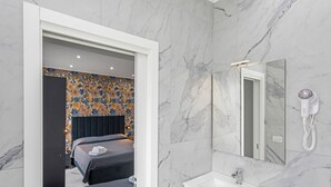 A hotel room with a marble bathroom, a bed with a dark headboard, and a hairdryer on the wall. - Room 'Dolce Relax - Tripla Luxury' with Wi-Fi and Air Conditioning (Catania)