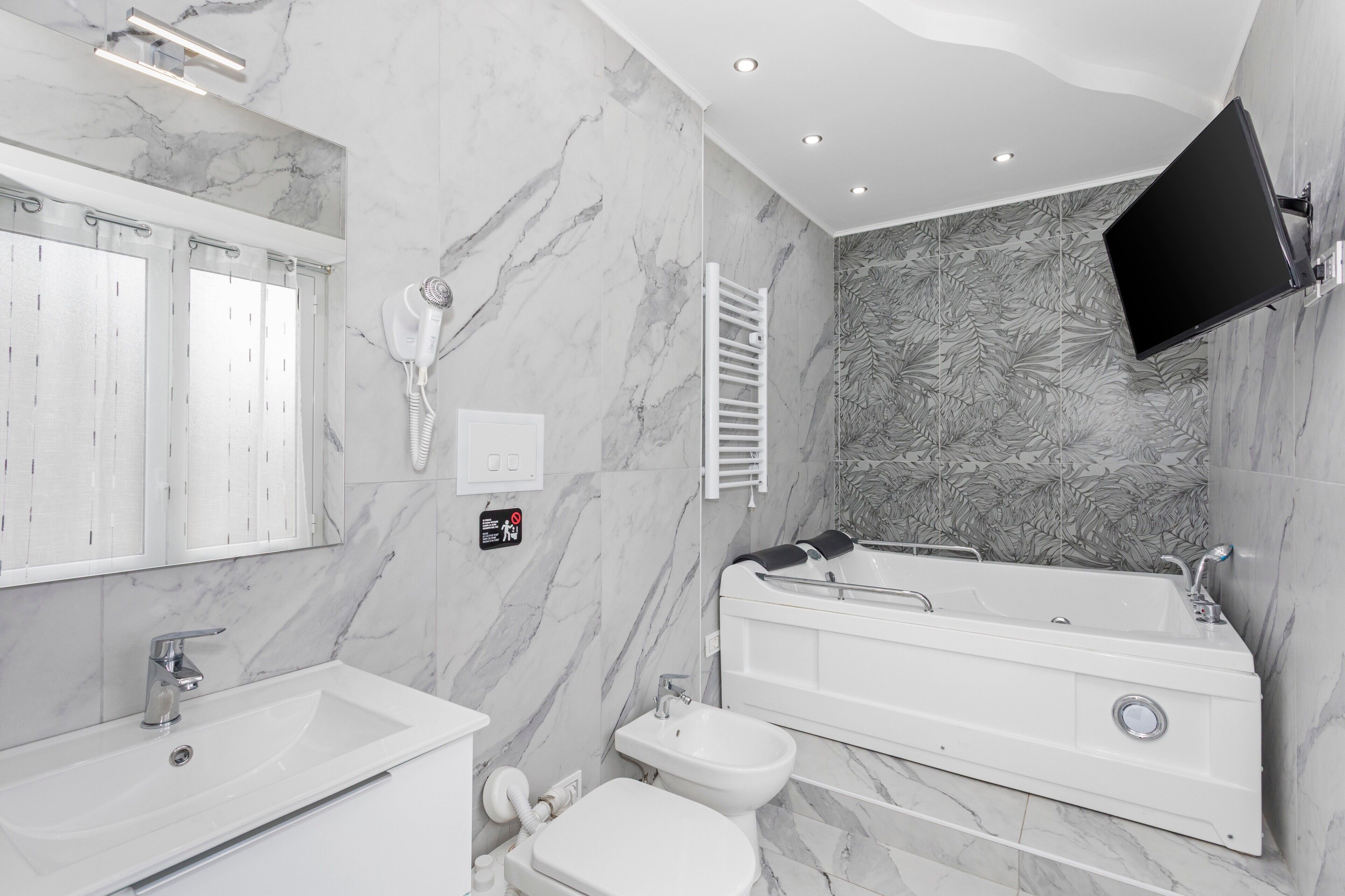 Un baño moderno con una bañera amplia, zona de ducha separada, inodoro y tocador con lavamanos.