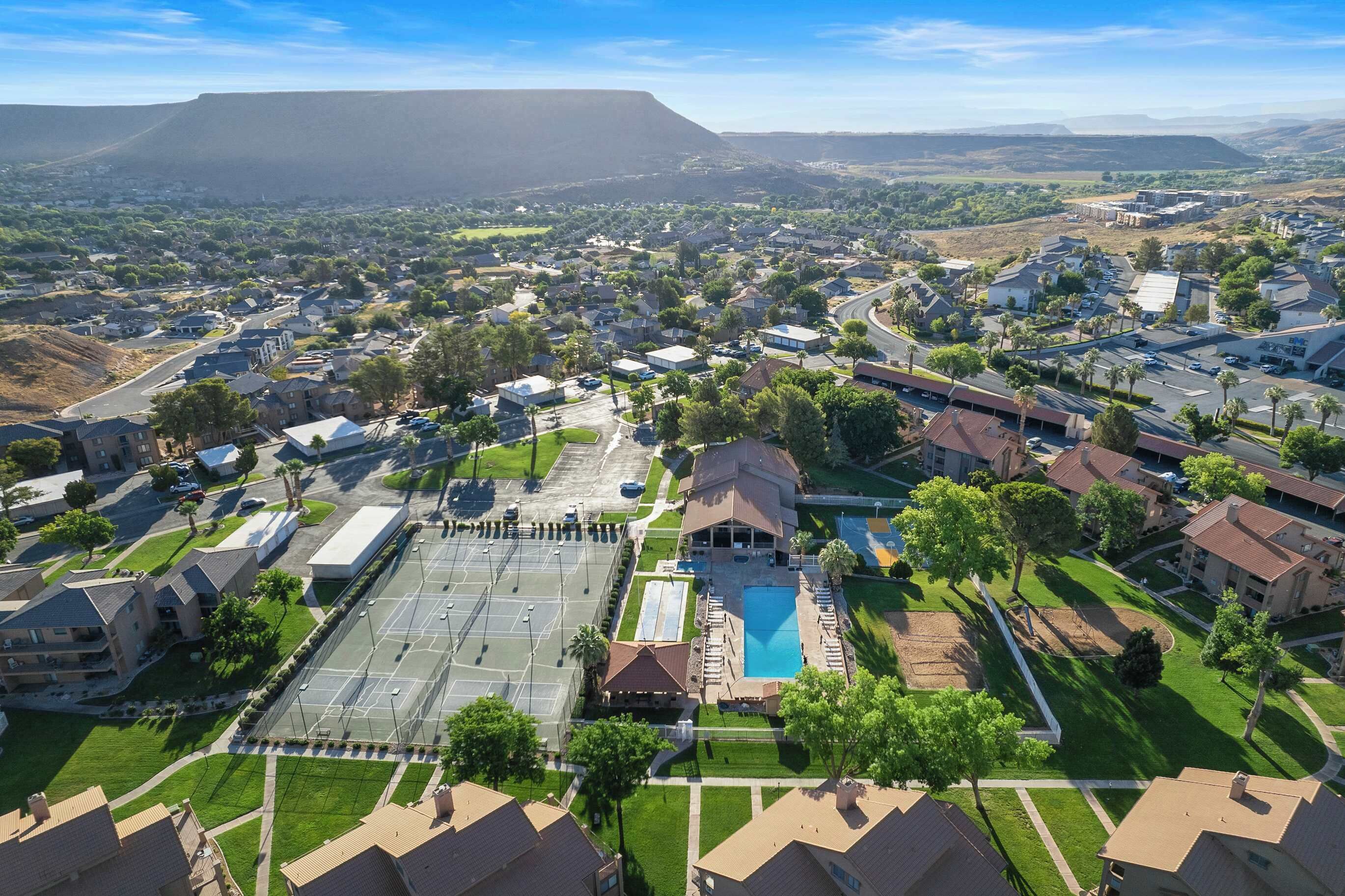 An aerial view of a residential area with houses, a large parking lot, and a swimming pool.