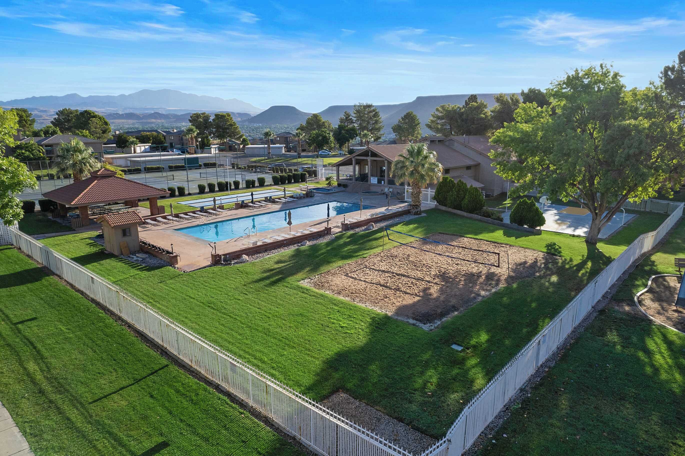 A residential area with a swimming pool, well-maintained lawn, and a view of distant mountains.