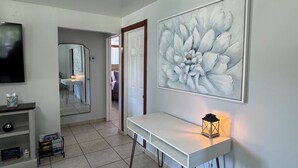 Una sala moderna con una obra de arte grande, una consola blanca y un televisor.