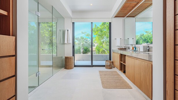 A modern bathroom with a glass shower enclosure, a wooden vanity, and a large window offering a view of greenery. - Golf-View Luxury Villa with Pool, Chef Service and Premier Golf in Punta Mita (Nayarit)