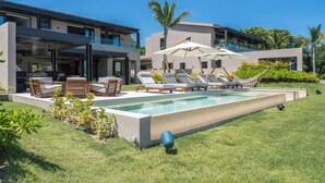 A modern poolside area with lounge chairs, a barbecue setup, and a large pool. - Golf-View Luxury Villa with Pool, Chef Service and Premier Golf in Punta Mita (Nayarit)