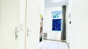 A hallway with white walls, a door, a radiator, a window with a view, and a painting. - Cozy Private Room | Shared Flat Near FAC Platz (Vienna)
