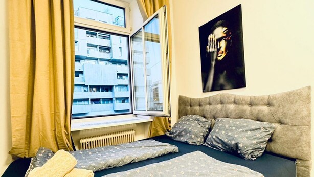 A bedroom with a bed, a window with curtains, a radiator, and a wall-mounted artwork. - Cozy Private Room | Shared Flat Near FAC Platz (Vienna)