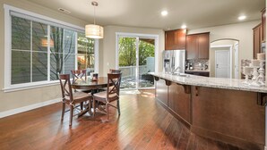Una cocina moderna con una isla grande, armarios de madera y un comedor con mesa y sillas.
