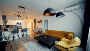 Een moderne woonkamer met een gele bank, een bijzettafeltje en een eethoek met stoelen en een tafel.