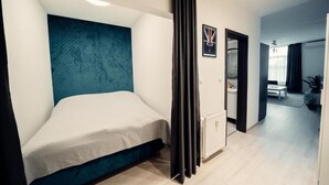 Een moderne hotelkamer met een eenpersoonsbed, een groot raam en uitzicht op de gang.