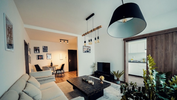 Een moderne woonkamer met een bank, salontafel en hanglamp.
