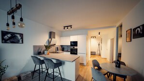 Een moderne keuken met een centraal eiland, barstoelen en een eethoek met een tafel en stoelen.