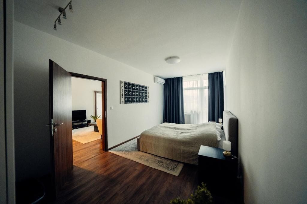 Een slaapkamer met een bed, een televisie, een wandairconditioner en een deur naar een andere kamer.