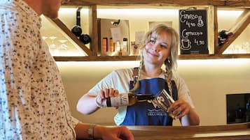 Baaritiskialue, jossa on puuhyllyt, joilla on esillä erilaisia pulloja, sekä liitutaulusta tehty ruokalista.