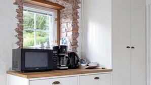 Una cocina con pared de ladrillo, una ventana y un armario blanco con cajones.