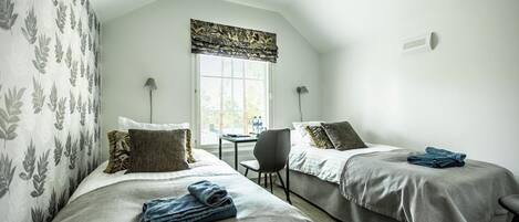 A room with two beds, a table, and a chair.