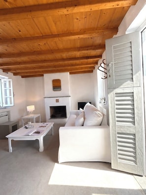 Un salon moderne avec une cheminée, des meubles blancs et un plafond en bois.