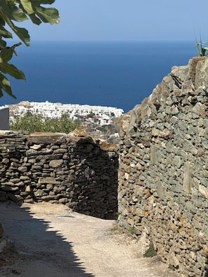 Un sentier de pierres mène à une ville côtière aux bâtiments blancs, d’où l’on peut admirer la mer.
