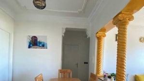 En matplats med ett träbord och stolar, en kristallkrona och en tavla på väggen.