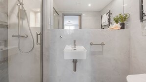 A modern bathroom with a glass-enclosed shower, a white sink, and a toilet.