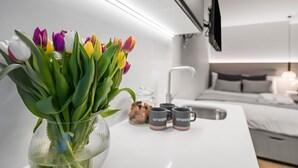 A modern hotel room with a bed, bedside table, and a vase of tulips.